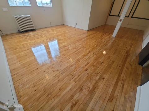 After — the same light wood floor, with the former-wall footprint less visible